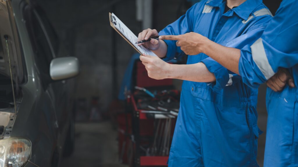 Two professional car mechanics looking at car inspection papers together, all types of car specialis